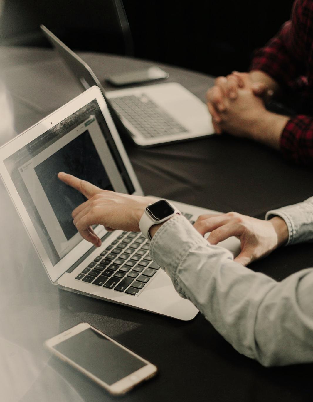 two people sitting at a table with laptops